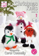 Load image into Gallery viewer, Image of cover of King Cole Christmas Knits book 10. 3 toys knitted in tinsel yarn - penguin with green scarf, orange feet and beak. A robin with long legs and black with white fur trim boots and Santa hat. The snowman has a red scarf and tea bag hat