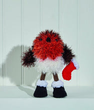 Load image into Gallery viewer, Tinsel robin with orange breast, brown wings and white lower body. Its stick legs are brown with black boots with a white fur top. It holds a red stocking with white trim. The legs, boots and stocking are DK yarn and the toy is knitted in tinsel