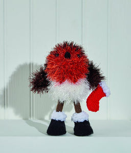 Tinsel robin with orange breast, brown wings and white lower body. Its stick legs are brown with black boots with a white fur top. It holds a red stocking with white trim. The legs, boots and stocking are DK yarn and the toy is knitted in tinsel