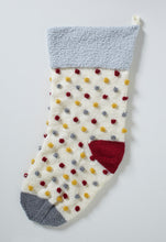 Load image into Gallery viewer, Image of a large festive holiday stocking with a light silver fur texture band and a hanging loop. Knitted in cream DK yarn with a dark red heel and dark grey toe piece. The bobbles are all over the cream section and are knitted grey, red and mustard
