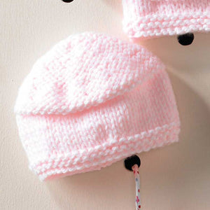 Image of a chunky baby hat in pale pink King Cole Comfort chunky yarn. The rim of the hat and crown are knitted in garter stitch and the sides are knitted in stocking stitch