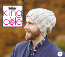 Load image into Gallery viewer, Image of a man wearing a slouchy rib beanie hat. The hat is hand knitted in a cream Aran yarn with dark flecks