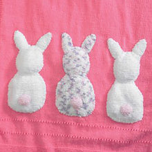 Load image into Gallery viewer, Crop of the 3 rabbit backs sewn in a row at the bottom of the plain blanket. The left and right rabbits are knitted in white faux fur with a pale pink pompom tail. The middle rabbit is knitted in white with purple and pink flecks and a pale pink tail

