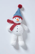 Load image into Gallery viewer, Fun Snowman toy knitted in a fake fur white yarn for added snowy texture. He had 3 black dots down his front and an orange carrot nose. His dark red scarf is knitted in garter stitch and his blue hat has a red band and red pom pom