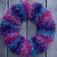 Load image into Gallery viewer, Tinsel festive wreath to hand on your door at Christmas. Knitted in bands of colourful tinsel - pink with silver flecks, turquoise and purple and turquoise mix.