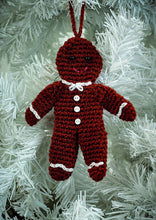 Load image into Gallery viewer, Crocheted gingerbread man Christmas tree ornament., Crocheted in a rich brown yarn with matching hanging hook. Black bead eyes and a pink embroidered mouth. White chains at his neck, wrists and ankles look like icing. 3 white buttons down his front