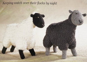 Image of two knitted sheep from the Alan Dart Nativity knitting pattern. There is one design but the image show two colour options - white coat with black face and legs; dark grey coat with light grey face and legs