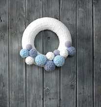 Load image into Gallery viewer, Beautiful icy effect wreath. The main ring is covered in a white chenille like yarn and around the bottom are a selection of pom poms and crocheted balls in different sizes and a mix of lilac, light blue, dusky blue and white