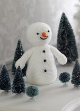 Load image into Gallery viewer, amigurumi crochet snowman. He is crocheted in white sparkle yarn with 3 black beads down his front and for his 2 eyes. He has a carrot cone 3D nose and his mouth is embroidered in black. He has 2 arms but is basically a simple but fun snowman toy