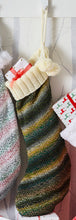 Load image into Gallery viewer, Smaller size stocking knitted in a self striping yarn that is a mix of greens and golds in a dark hue and finished with a cream ribbed cuff
