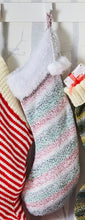 Load image into Gallery viewer, Image of smaller size Christmas stocking hand knitted in self striping super chunky yarn. The stripes are pink, green, grey and white and the top is knitted with white tinsel for a sparkly finish
