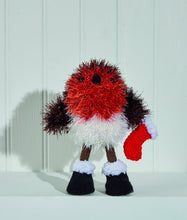 Load image into Gallery viewer, Tinsel robin with orange breast, brown wings and white lower body. Its stick legs are brown with black boots with a white fur top. It holds a red stocking with white trim. The legs, boots and stocking are DK yarn and the toy is knitted in tinsel
