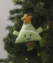 Load image into Gallery viewer, Fun Christmas tree ornament. Hand knitted in light green yarn using stocking stitch. It is a triangle shape with green arms and a brown trunk. A mouth and eyes have been added with a gold coloured star at the top
