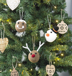 3 Christmas tree baubles shown hanging on a Christmas tree. A light brown putting with white top, black eyes and a white mouth. A reindeer with white twig antlers and a red nows, a snowman with a carrot nose and black top hat