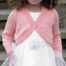 Load image into Gallery viewer, Close up image of young girl wearing a white dress and pink v neck bolero cardigan or shrug. The bolero has long sleeves and the yarn is interwoven with silver sequins to make it sparkle
