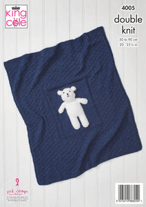 Image of a navy baby blanket. It has a diamond pattern knitted using garter stitch on to of stocking stitch - subtle because it is knitted all in one colour. There is a plain panel in the centre on which a white teddy bear is sewn