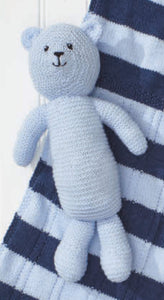 Close up image of a light blue teddy bear toy hand knitted in garter stitch. It matches the light blue yarn in the navy and light blue striped baby blanket it is lying on 