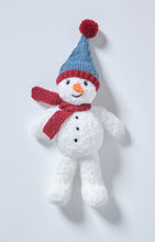 Load image into Gallery viewer, Fun Snowman toy knitted in a fake fur white yarn for added snowy texture. He had 3 black dots down his front and an orange carrot nose. His dark red scarf is knitted in garter stitch and his blue hat has a red band and red pom pom 
