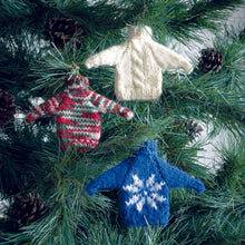 Load image into Gallery viewer, Mini Christmas jumper decorations hanging on a Christmas tree. White with a cable twist down the front, plain in a self striping festive yarn with white, green, red and a silver sparkle. Royal blue with a white snowflake motif on the front
