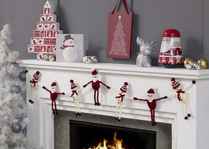 Super fun Christmas bunting hang on a mantlepiece. Alternating stick figure Santas and snowmen. They are knitted knit in dark red and white yarns. Santa has a bauble hat and the snowman's hat is striped with a red pom pom and a red scarf