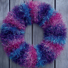 Load image into Gallery viewer, Tinsel festive wreath to hand on your door at Christmas. Knitted in bands of colourful tinsel - pink with silver flecks, turquoise and purple and turquoise mix. 

