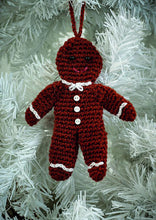 Load image into Gallery viewer, Crocheted gingerbread man Christmas tree ornament., Crocheted in a rich brown yarn with matching hanging hook. Black bead eyes and a pink embroidered mouth. White chains at his neck, wrists and ankles look like icing. 3 white buttons down his front
