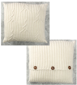 A simple cable design cushion or pillow knitted in white yarn. The knots and twists look a little like antlers. On the back, the two pieces are closed about a third up from the bottom with round wooden buttons