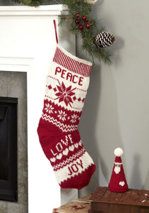 Scandinavian style knitted Christmas stocking and cone shaped red santa toy with a white hard motif and pom pom. The stocking is knitted in white and red DK yarn with panels of snow flakes, zig zags and the words Peace, Love and Joy