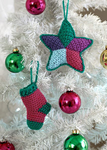 2 Christmas tree ornaments pictured on a white Christmas tree. The pink mini stocking has green heel, toe, cuff and hanging loop. The five-point star has coloured diamond segments - light blue, purple, green, pink and violet - with green edging