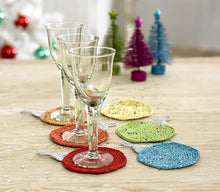 Load image into Gallery viewer, Like the tea cosy, these drink coasters are designed to look like Christmas baubles. There are six shown - yellow, light orange, orange, red, blue and green. The yarns sparkle with coloured flecks. The top of the circle is a silver bauble top
