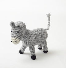 Load image into Gallery viewer, Crocheted donkey in light grey yarn. Its nose is white with 2 black nostril details and black bead eyes. His ears and tail are light grey and his hooves are black
