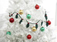 Load image into Gallery viewer, Crocheted holly leaf garland pictured on a white Christmas tree. Each holly leaf is crocheted in dark green DK yarn and attached to the matching cord with a red berry
