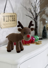 Load image into Gallery viewer, Amigurumi reindeer toy. Red nosed reindeer crocheted in brown yarn. His muzzle is light brown and his antlers are dark brown, as are his hooves. His eyes are black beads and he is finished off with a bright red nose. Cute and fun Xmas toy to gift
