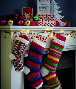 3 crocheted Christmas stockings. All with white toes, heels and tops. Small stocking is crocheted in a self striping yarn with green, red and white. Medium stocking is latticed stripes in reds and blues. Large stocking is stripes of red, green, gold