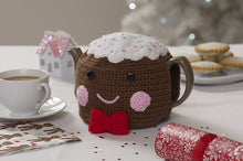 Load image into Gallery viewer, Fun Christmas pudding tea cosy. The main pudding is crocheted in brown yarn with black button eyes and embroidered pink mouth and cheeks. The top is white with coloured sprinkles and the finishing touch is a red bow tie on the front at the bottom
