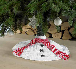 A snowman tree skirt pictured on a Christmas tree. Knitted in whit yarn with 3 large knitted buttons and a red and white striped garter stitch scarf with tassels